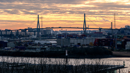 Fototapeta na wymiar Stunning panoramic view of the Port of Hamburg with the container terminal and the Köhlbrandbrücke bridge at Elbe river at sunset from the roof of Dockland