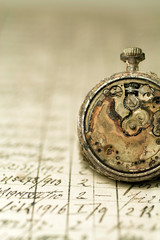 Rusted antique pocket watch on an old notebook