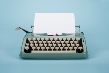 Retro old typewriter with paper on light blue background