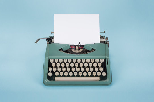 Retro old typewriter with paper on light blue background