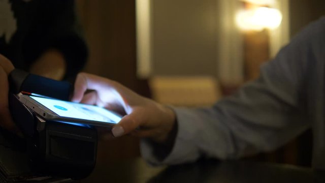 Women's hands close-up pay in a cafe using the terminal with their smartphone, contactless payment system