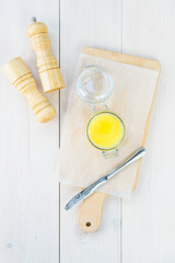 Ghee butter in a jar on a wooden board. Vertical orientation, top view.