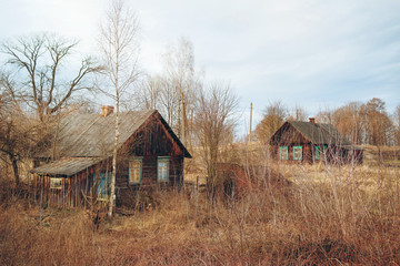 Two old rustic wooden houses in an abandoned village in early spring