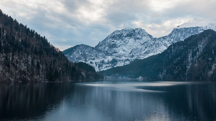 Fototapeta na wymiar Winter lake Ritsa in Abkhazia with mountains in the snow in the background, late evening.