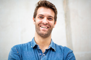  front portrait smiling man with blue shirt by white wall
