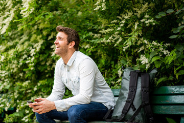 Obraz premium older man sitting outside on park bench holding cellphone