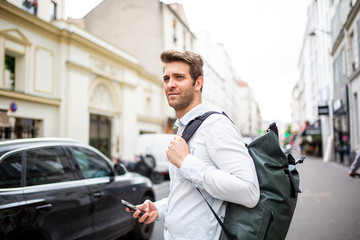 Side of handsome man in city with mobile phone and bag