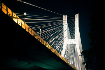 Suspension bridge at night on illuminated iron cables in Wroclaw