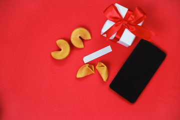 Valentine's day celebration concept. Phone, fortune cookies and a gift in white packaging with a...