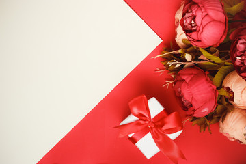 Valentine's day celebration concept. Gift with a bouquet of pink flowers on a double white-red background with space for your text.