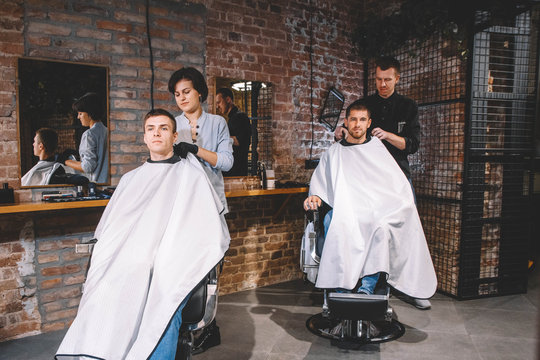 Hairdressers cut their clients in barbershop. Advertising and barber shop concept