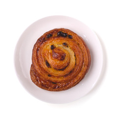 A plate with fresh delicious bun with raisins isolated on white background