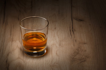 A glass of whiskey on a wooden table. Space for text.