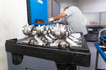 New parts of a car manufactured in the factory, blurred automotive worker at work