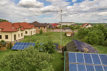 Aerial view of a residential private house with solar panels on roof and wind generator turbine. © bilanol