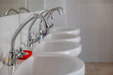 White ceramic washing basins with shiny stainless steel water tap.