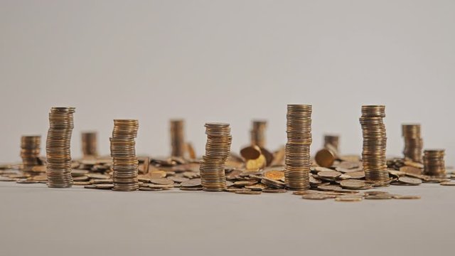 The concept of money. Columns of gold coins in the form of skyscrapers or Stonehenge. Close-up hands make up stacks of coins. Smoke. Garland.