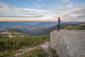 Obraz premium Young child boy hiker standing in mountains enjoying view of amazing mountain landscape.