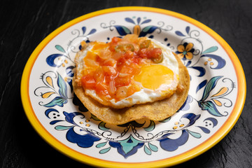 Mexican egg mounted on corn tortilla with sauce also called 