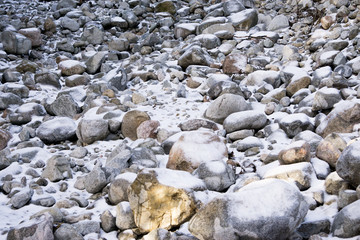 A lot of stones in the snow. Difficult route in the mountains
