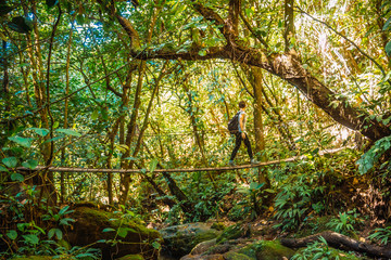 A young woman crossing a wooden bridge of the Cerro Azul Meambar National Park (Panacam) in Yojoa. Honduras