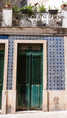 Old, traditional Portuguese entrance way with an old green painted door and blue traditional tiles. Taken in summer in Lisbon.
