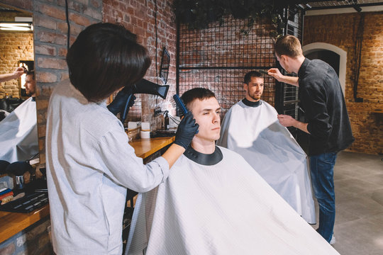 Hairdressers cut their clients in barbershop. Advertising and barber shop concept