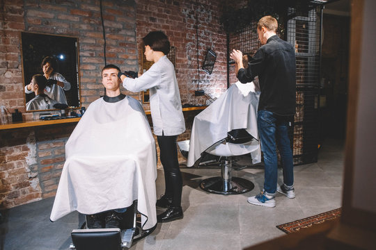 Hairdressers cut their clients in barbershop. Advertising and barber shop concept