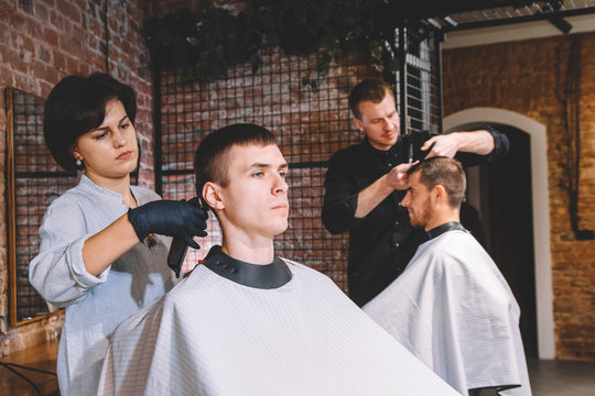 Hairdressers cut their clients in barbershop. Advertising and barber shop concept