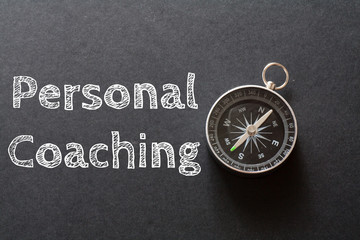 Written Personal Coaching words on black background with compass