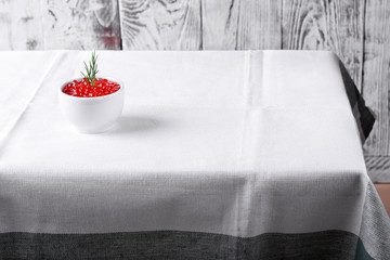 Red caviar in the little ceramic bowl on the edge of the table with white tablecloth - Powered by Adobe