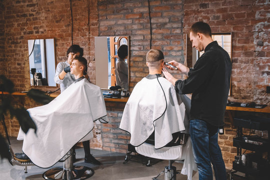 Hairdressers cut their clients in barbershop. Advertising and barber shop concept