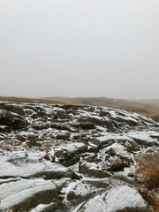 Adventure hike to the scenic landmark of the Gullfoss Waterfall on the Golden Circle Route in Iceland: beautiful nordic autumn / winter landscape with snow covered rocks, bushes and a foggy sky