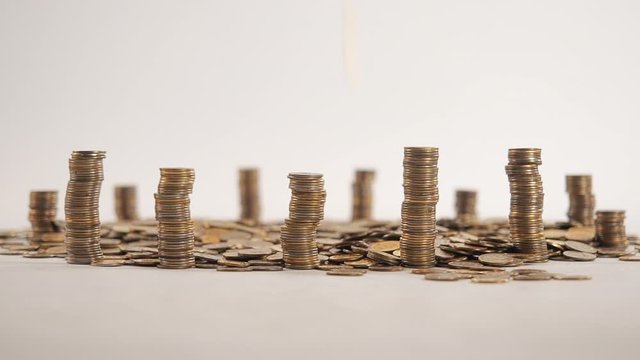 The concept of money. Columns of gold coins in the form of skyscrapers or Stonehenge. Close-up hands make up stacks of coins. Smoke. Garland.