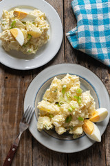 Potato salad with egg and mayonnaise on wooden background