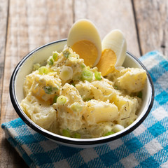 Potato salad with egg and mayonnaise on wooden background