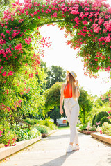 girl with long hair and boater in the park under the flower arch