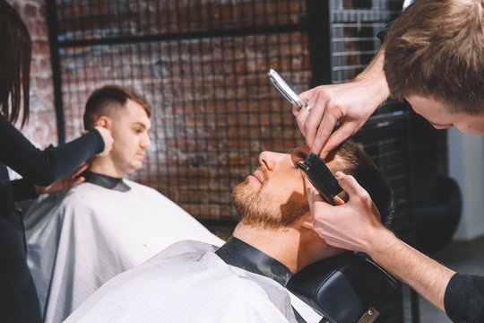 Hairdressers cut their clients in barbershop. Advertising and barber shop concept