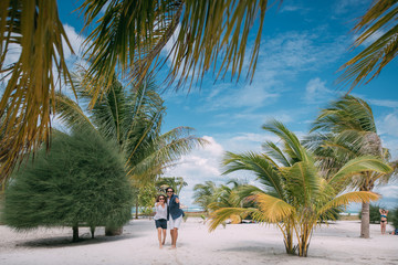 A pair of lovers are walking on a tropical beach.