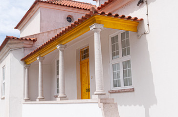 Traditional white & yellow Portuguese home with pillars.