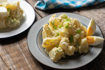 Potato salad with egg and mayonnaise on wooden background