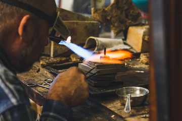 Jeweler at work with a propane burner in a jewelry workshop. Fire close up.