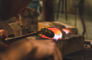 Jeweler at work with a propane burner in a jewelry workshop. Fire close up.