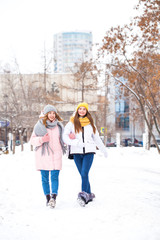 Fototapeta na wymiar Full-length portrait of two young girls walking in a winter park