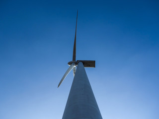 tall wind turbine bottom view under clear blue sky with copy space