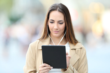 Fototapeta premium Serious woman e-learning using tablet and earbuds