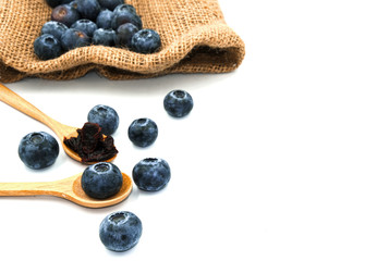 group of blueberry fresh fruit on bag sack. dried berry on wooden spoon. Isolated on white background