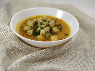  Pumpkin cream soup with hard chucks in a white plate