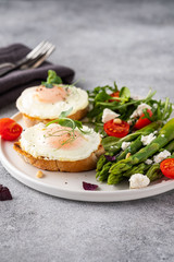 Obraz na płótnie Canvas Egg and green asparagus on toast with greens. Healthy breakfast.