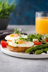 Egg and green asparagus on toast with greens. Healthy breakfast.